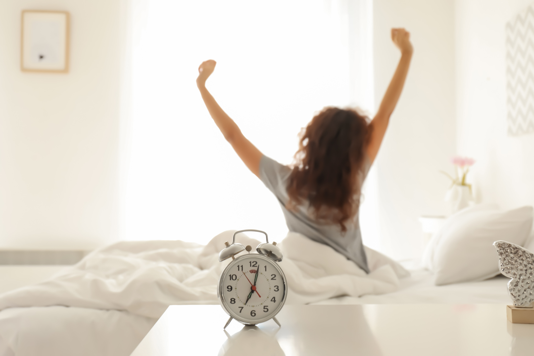 Alarm Clock on Table in Bedroom of Beautiful Young Woman. Morning Time